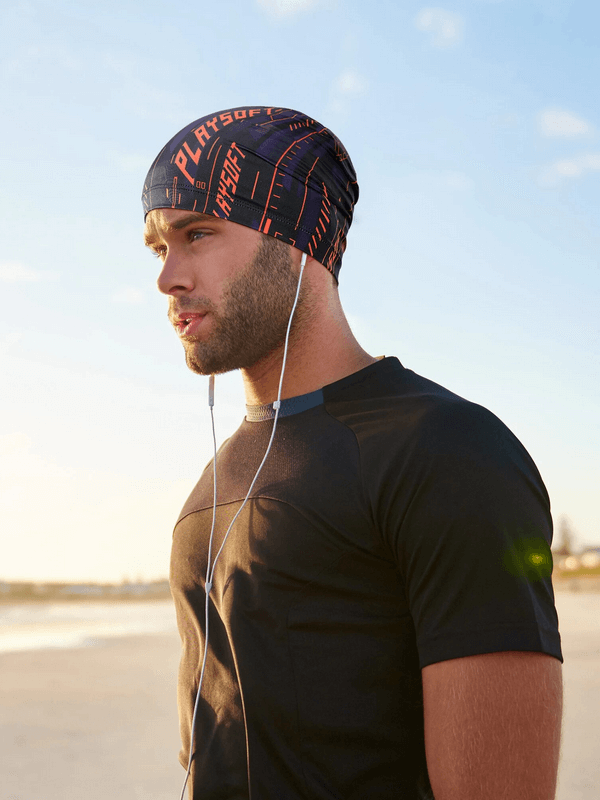 Man wearing breathable elastic men's printed beanie with earphones, enjoying a sunny day at the beach.
